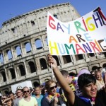 A woman holds her banner in front of the Colosseum during the annual gay pride parade in downtown Rome