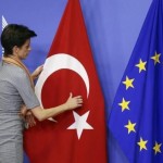 A woman adjusts the Turkish flag next to the EU flag before the arrival of Turkish PM Davutoglu at the EU Commission headquarters in Brussels